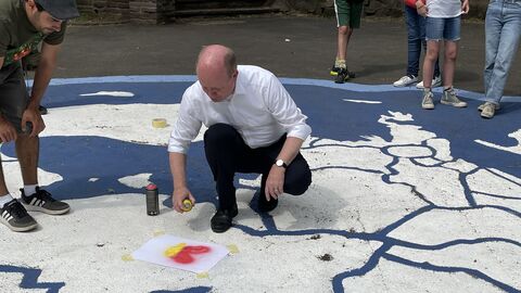 EU-Projekttag 2022 an der Albert-Schweitzer-Schule Kassel Europastaatssekretär Uwe Becker hält eine Schablone beim Sprühen einer EU-Karten am Asphalt