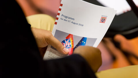 Ein Gast hält das Programm des Abends in der Hand