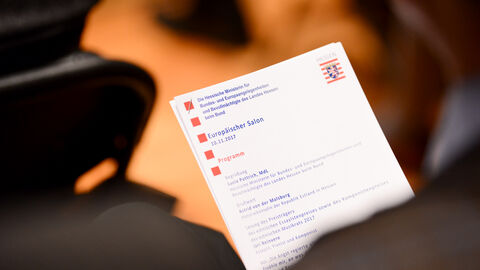 Ein Gast hält das Programmheft des Abendes in der Hand