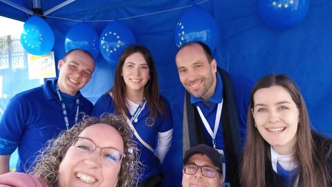 Es sind sechs Mitarbeiterinnen und Mitarbeiter des Europe Direct Darmstadt und der Hessischen Staatskanzlei im Inneren des Info-Standes zu sehen.