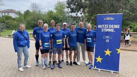 Die Läuferinnen und Läufer des Europe Direct NordOstHessen es sind neun Personen mit einem Roll-Up zur Europawahl zu sehen, acht von Ihnen tragen Laufkleidung.