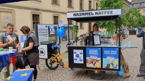 Das Kaffee-Fahrrad in Fulda Es ist ein Lastenfahrrad mit einer integrierten Kaffeetheke zu sehen, das auf dem Jesuitenplatz in Fulda steht. Hinter der Theke steht eine Frau.