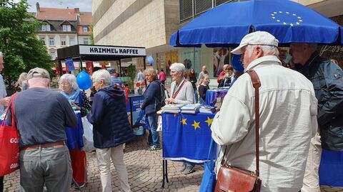Bürgerinnen und Bürger beim Kaffee am Infostand zur Europawahl Es sind mehrere Bürgerinnen und Bürger am Infostand zur Europawahl zu sehen; einige von ihnen trinken Kaffee.