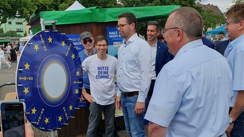 Beim Drehen des Glücksrads Auf dem Foto sind mehrere Männer zu sehen, die vor einem Glücksrad in Europafarben stehen.