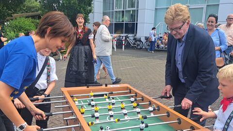 Beim Tischfußball-Spielen Ein Mann und eine Frau spielen mit zwei Jungen im Freien Tischfußball.