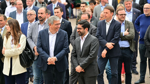 Oberbürgermeister Gert-Uwe Mende und Minister Kaweh Mansoori inmitten der Besuchenden Ausschnitt der Menge an Besuchenden vor der Bühne. Im Vordergrund sind Gert-Uwe Mende, Oberbürgermeister der Stadt Wiesbaden und Kaweh Mansoori, Hessischer Minister für Wirtschaft, Energie, Verkehr, Wohnen und ländlichen Raum und stellvertretender Ministerpräsident des Landes Hessen, zu sehen.