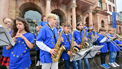 Musikbeitrag der Diltheyschule Schülerinnen und Schüler der Diltheyschule musizieren auf den Rathaustreppen. Alle tragen blaue Europa-T-Shirts mit einem gelben Sternenkreis.