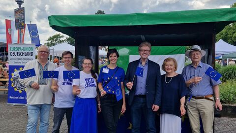 Vor dem Stand der Europa-Union Auf dem Foto sind sieben Menschen verschiedenen Alters und Geschlechts vor einem Infostand zu sehen; sie blicken alle in die Kamera.
